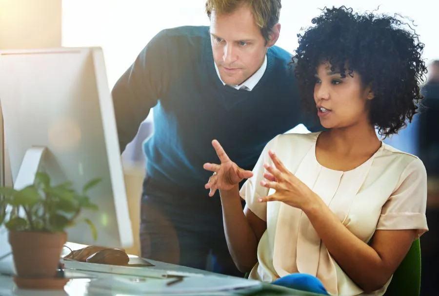 Young Black businesswoman showing a project on a computer to her Caucasian colleague.
